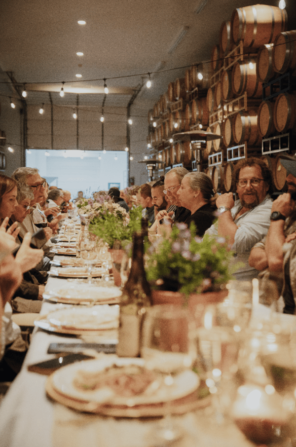 Guests at a long table at the RoxyAnn Winery Harvest Dinner chatting and enjoying dinner and wine.