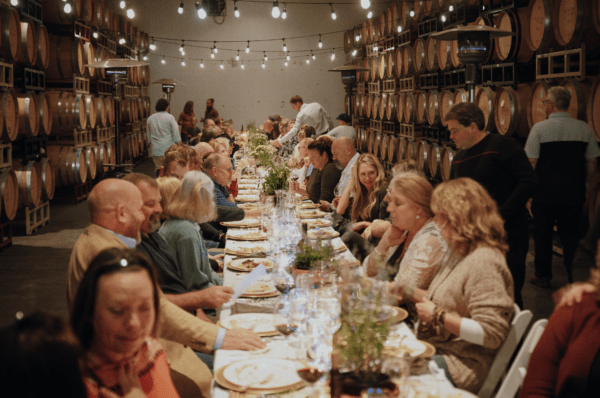 Guests at a long table at the RoxyAnn Winery Harvest Dinner chatting and enjoying dinner and wine.