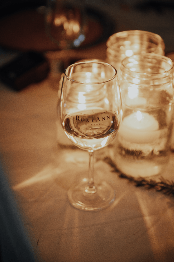 A close-up candlelight shot of a glass of white wine from RoxyAnn Winery in Medford, Oregon.