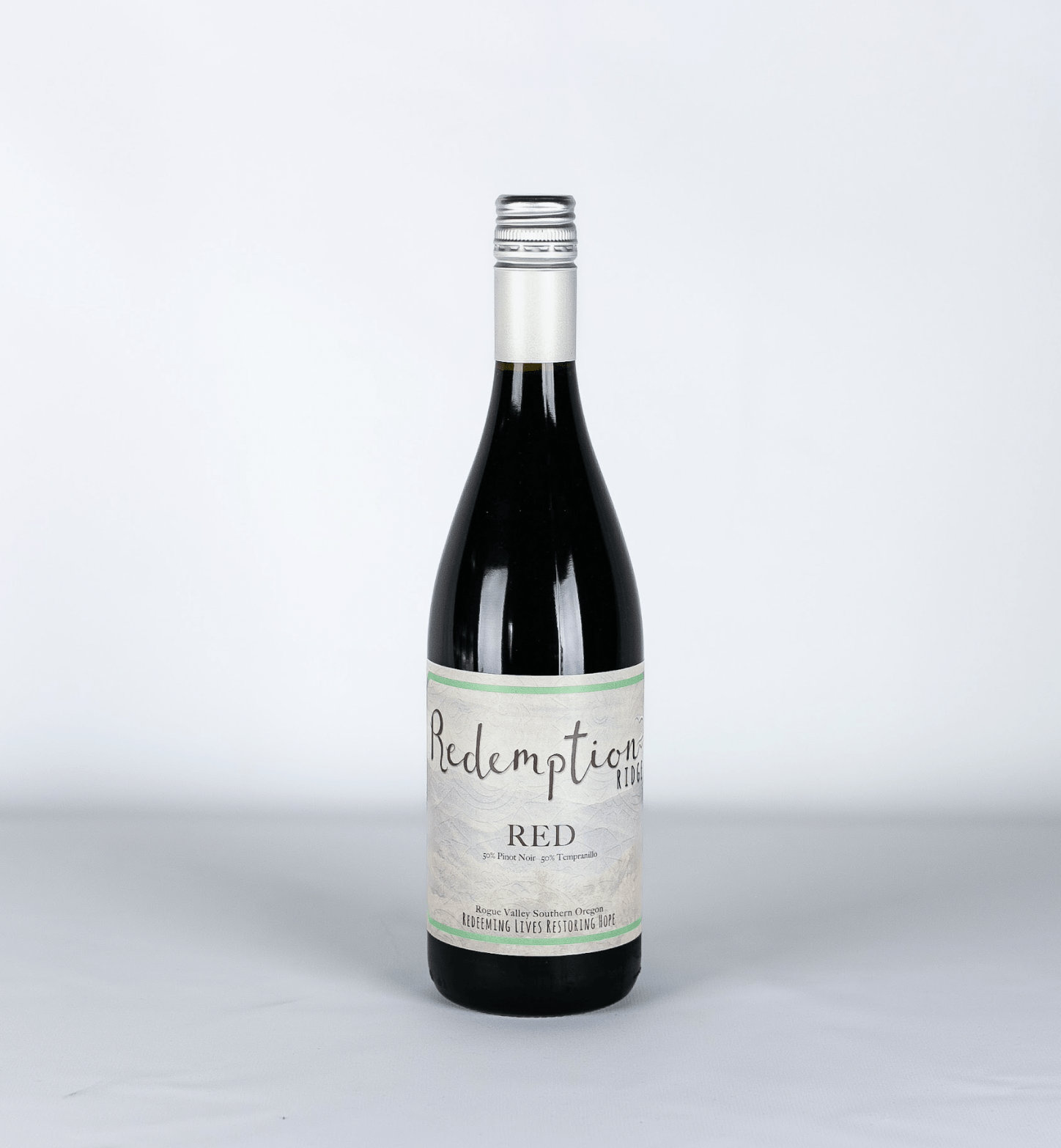 An image of the RoxyAnn Winery Redemption Ridge Red wine. A red blend of 50/50 Pinot Noir and Tempranillo. $10 of every bottle sold goes to supporting a nonprofit organization or charity in the Rogue Valley.